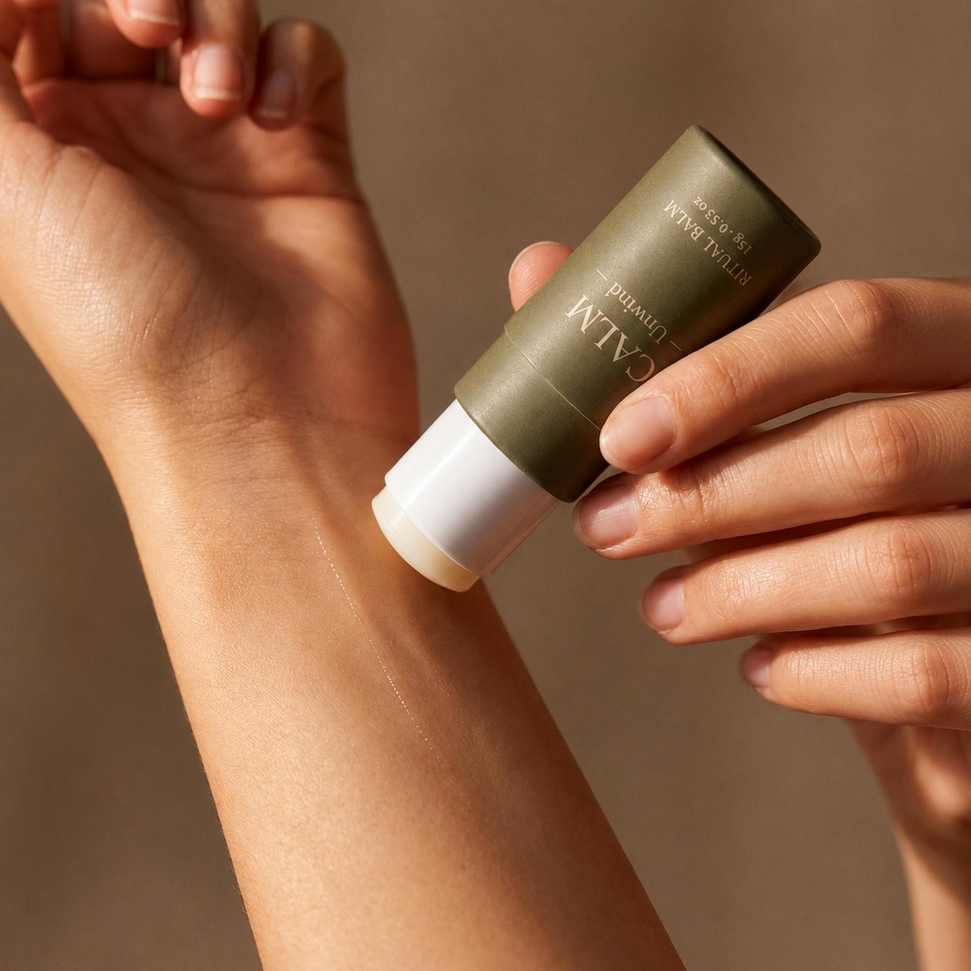 Applying AXOMYTH CALM ritual balm to the wrist, close-up