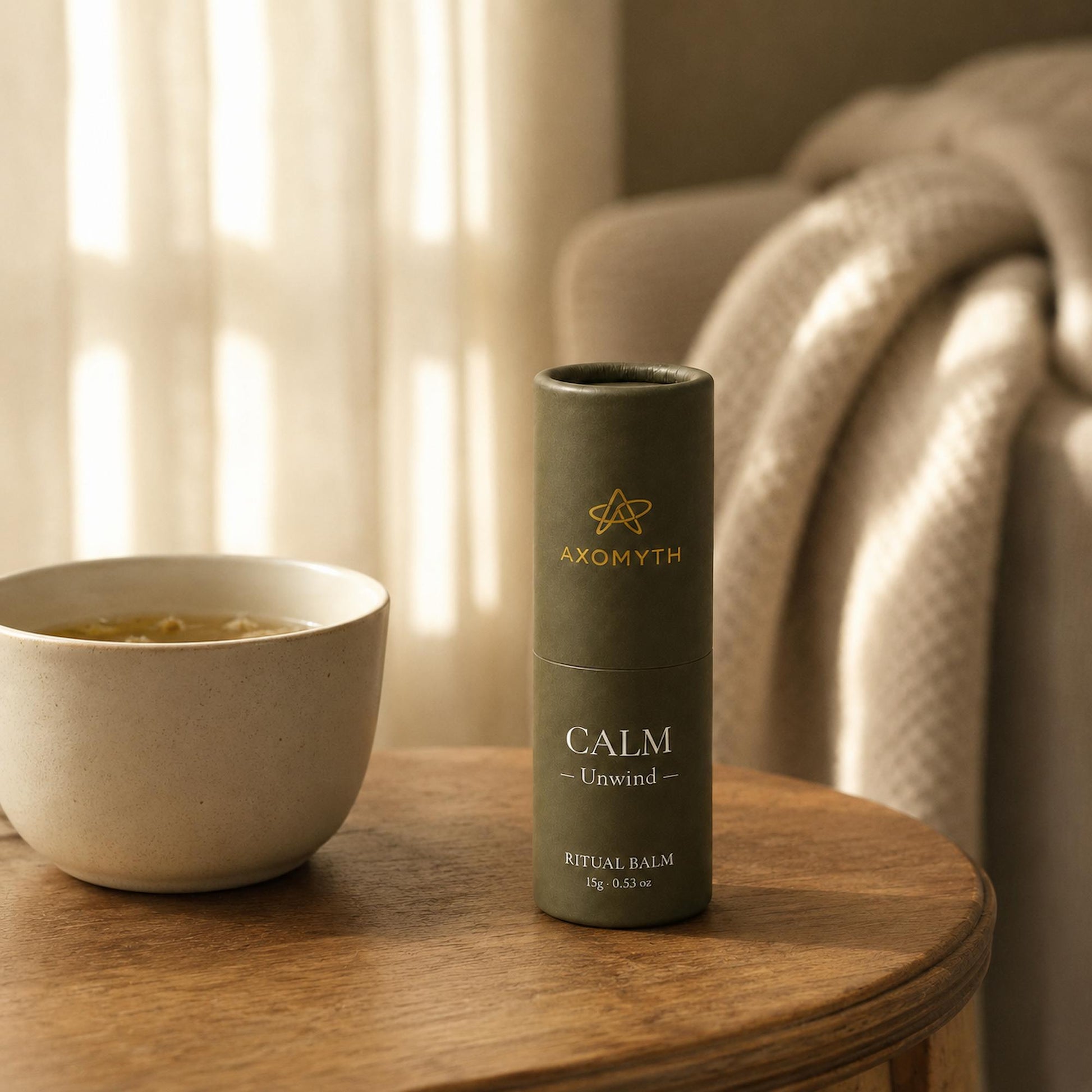 AXOMYTH CALM ritual balm beside herbal tea in a calm afternoon setting