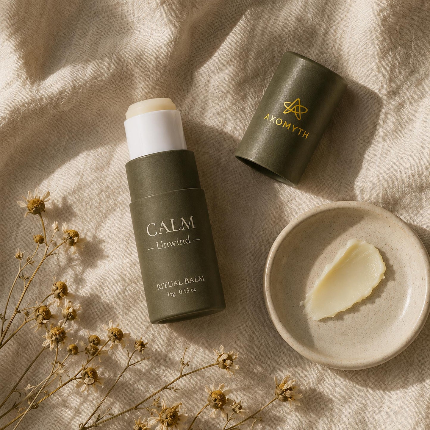 AXOMYTH CALM ritual balm flat lay with balm swatch, dried chamomile and linen