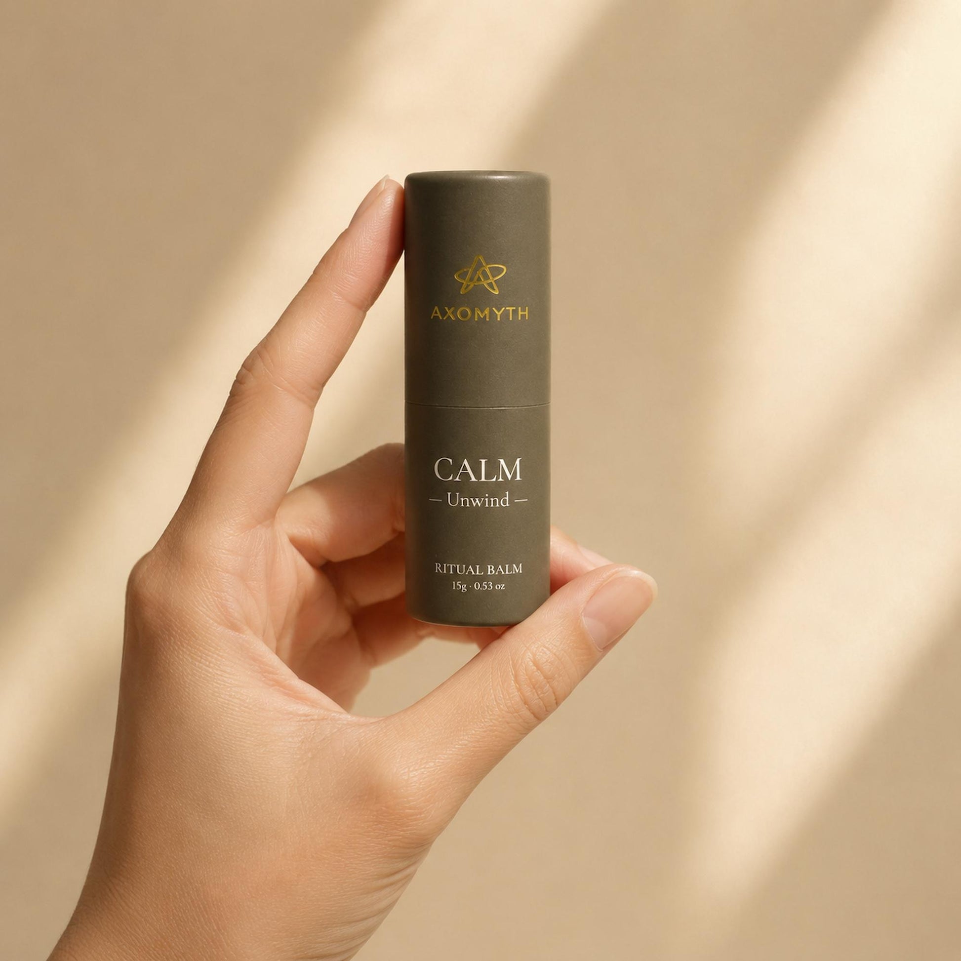 AXOMYTH CALM ritual balm held between fingers, showing true size