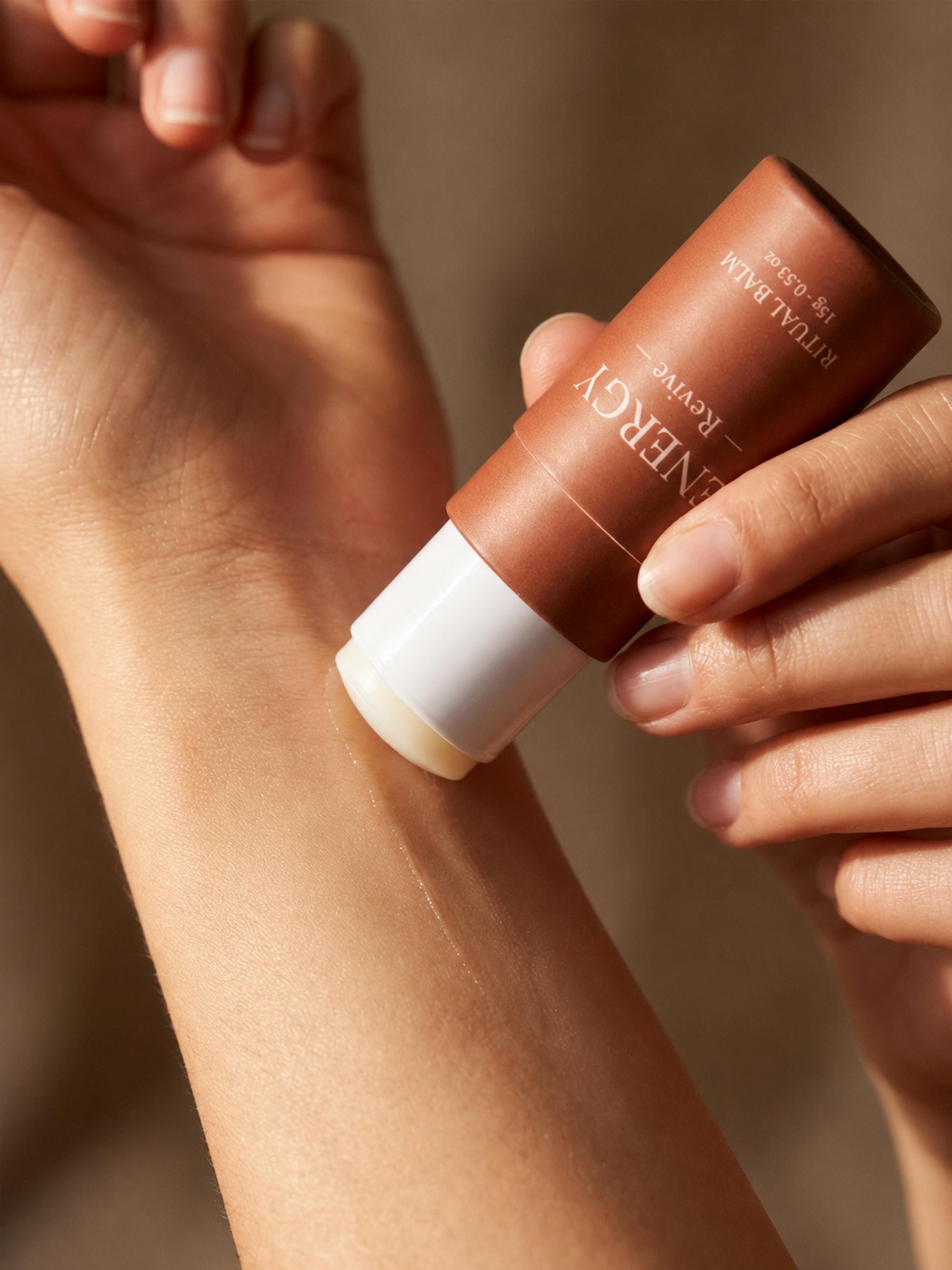 Applying AXOMYTH ENERGY ritual balm to the wrist, close-up