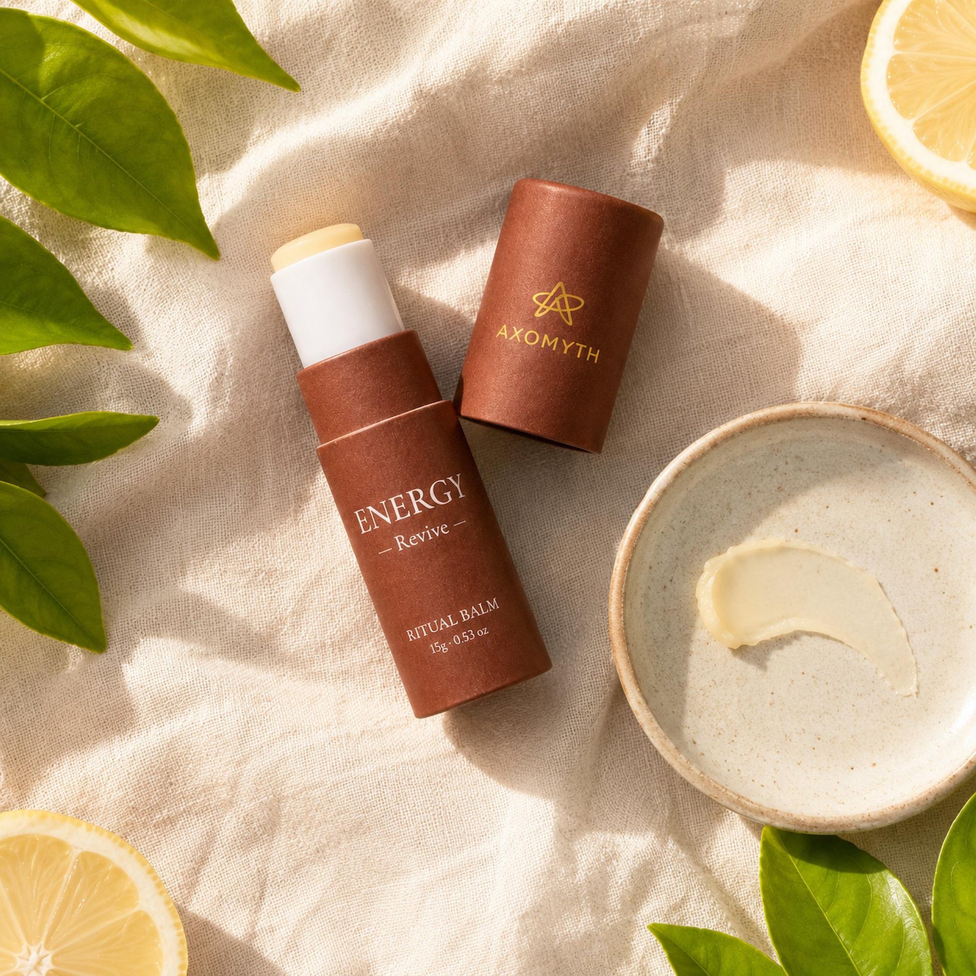 AXOMYTH ENERGY ritual balm flat lay with balm swatch, lemon and greenery