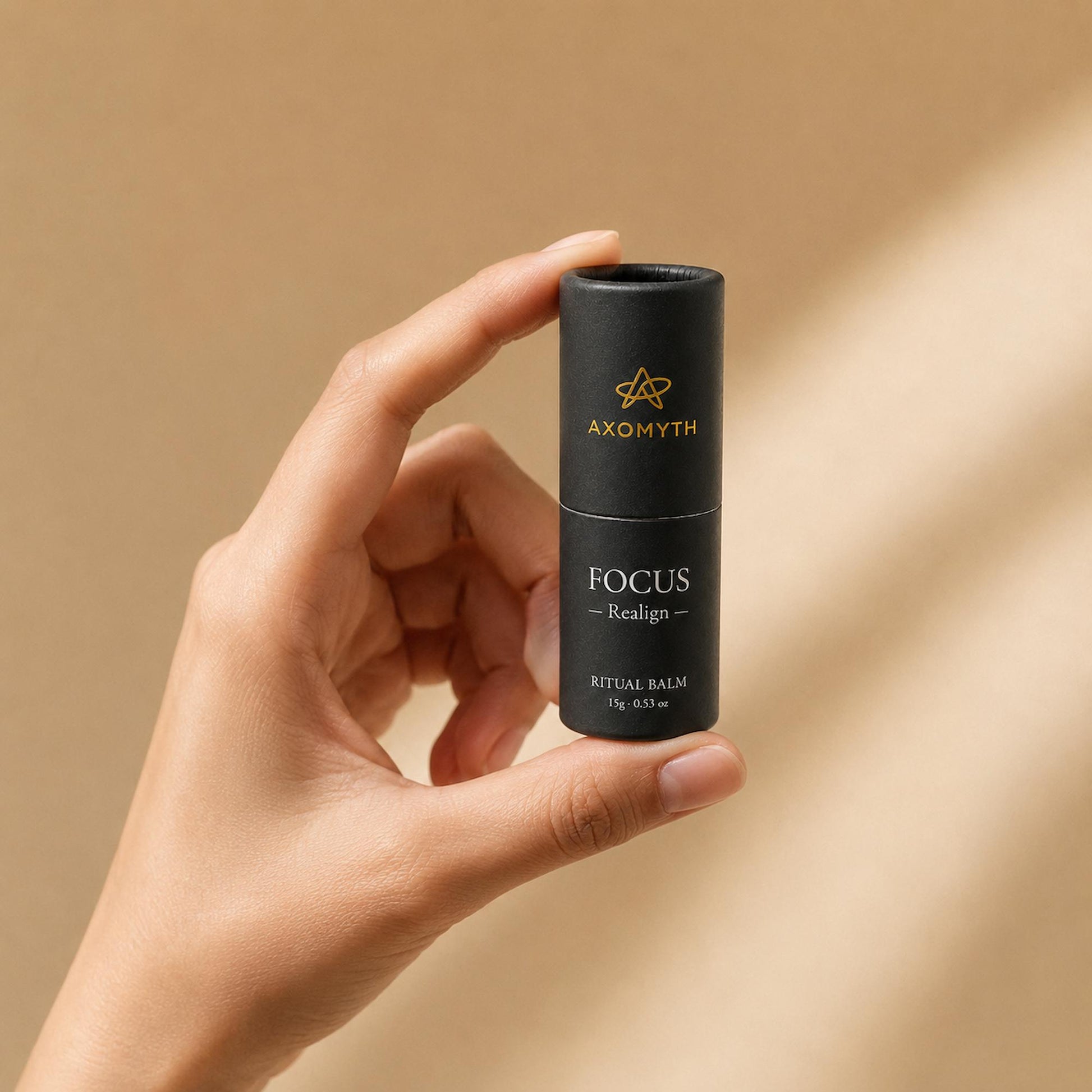 AXOMYTH FOCUS ritual balm held between fingers, showing true size